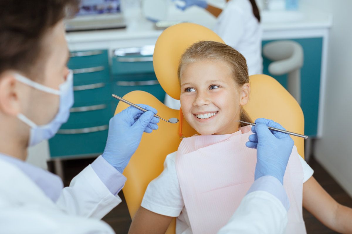 Child smiling at pediatric dental appointment with dentist