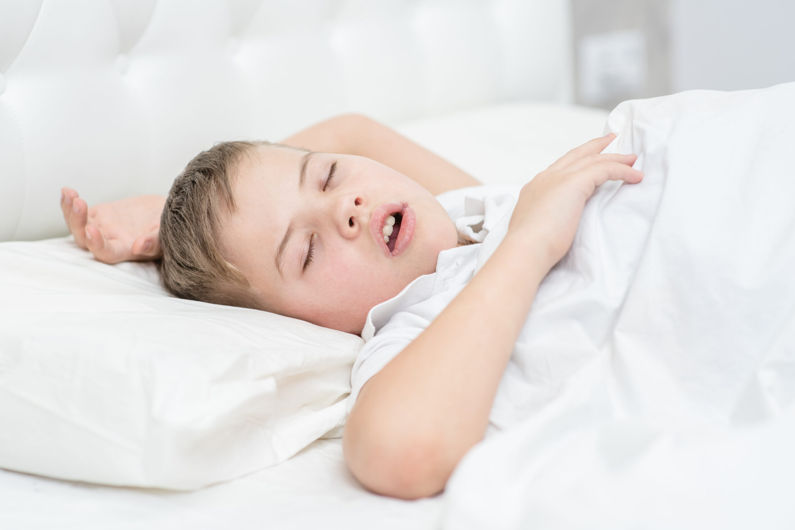 Young boy sleeping with his mouth open, a common sign of mouth breathing in children