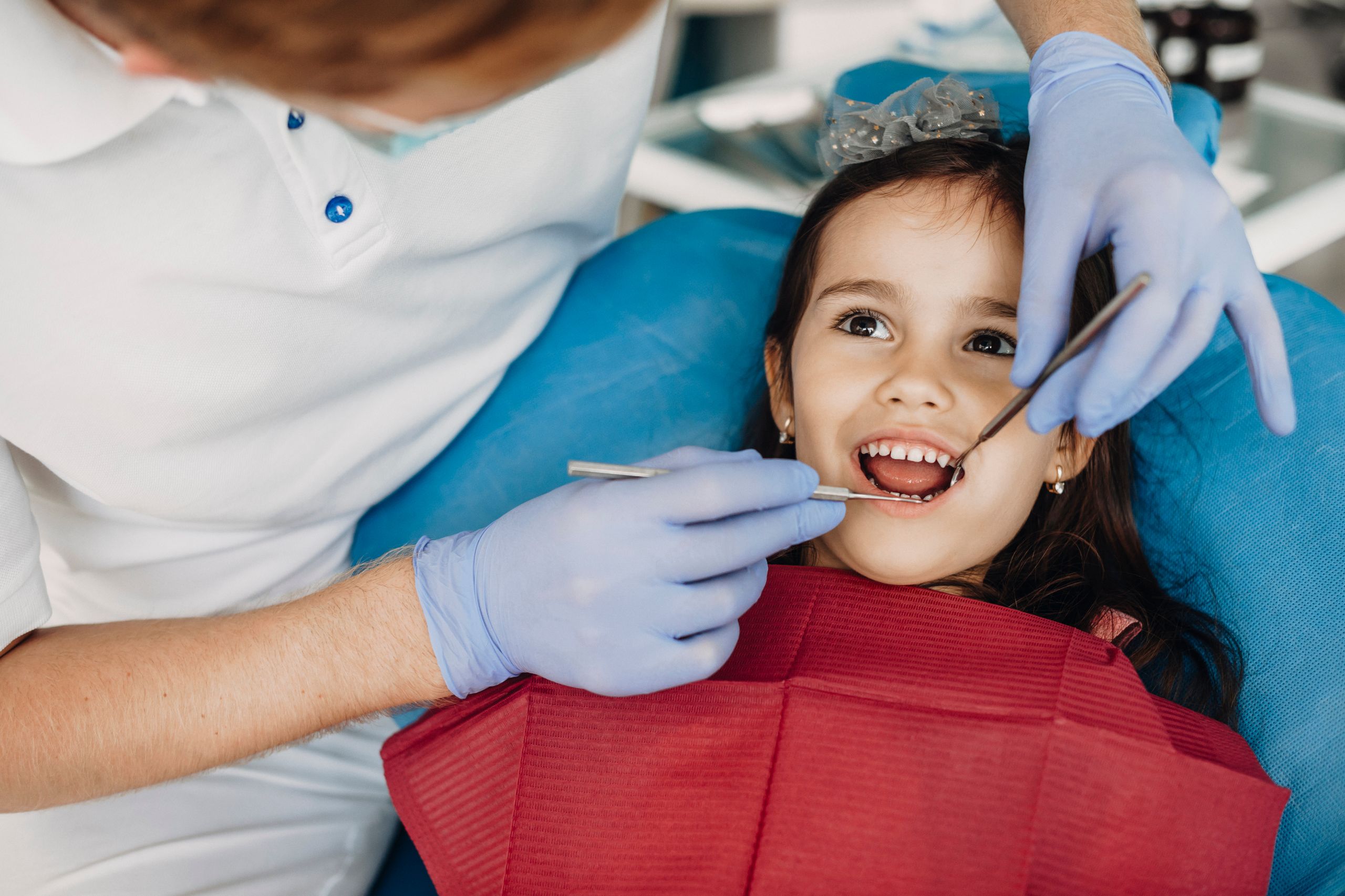Pediatric dentist checking a young child's teeth for cavities